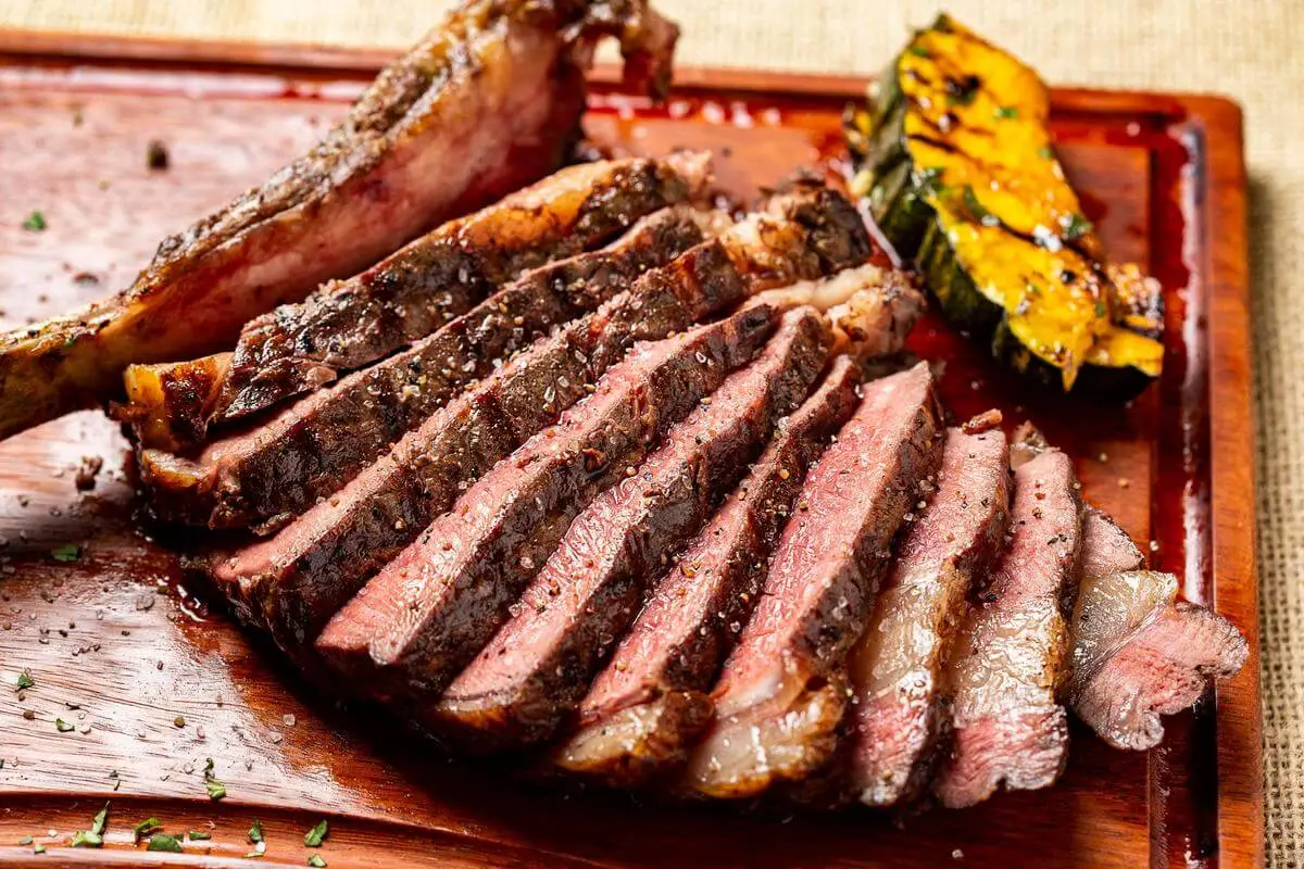 Fotografia de carne grelhada fatiada com abóbora na tábua